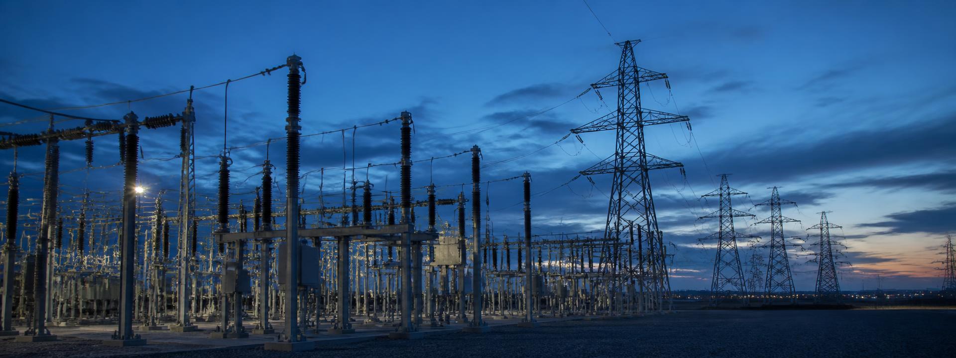 High-voltage electrical substation and transmission towers at dusk